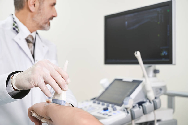 Examination of elbow with ultrasound probe. - Photo, image