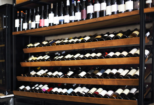 Bottles of wine on the shelves in a rack. Wine shop backgroun - Photo, Image