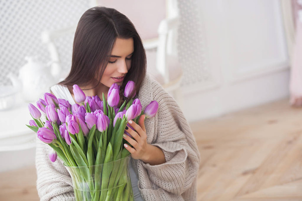 Close up portrait of young beautiful woman indoors. Attractive woman with flowers. Female with tulips. Spring bouquet. - Foto, Bild