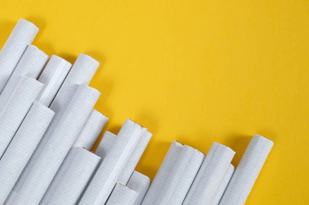 Several cigarettes carelessly lie at an angle on a yellow background. Top view. Copy space. - Foto, imagen