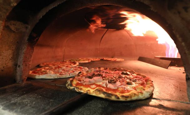 oven en pizza verwijderd uit de Italiaanse pizza-maker met een speciale schop - Foto, afbeelding