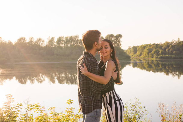 Relationship, love and nature concept - Attractive woman and handsome man hugging and kissing over water background - Photo, Image