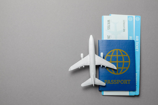Tickets voor vliegtuig en paspoort met model van passagiersvliegtuig op grijze achtergrond. Ruimte voor tekst kopiëren - Foto, afbeelding