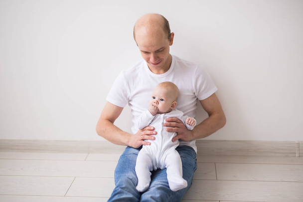 Concepto de bebé, familia e hijos: el padre calvo cuida de su pequeño bebé
 - Foto, Imagen