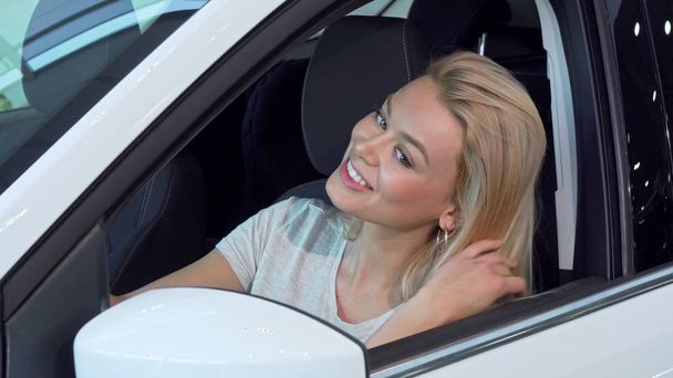 Prachtige vrouw zitten in een auto, kijken in de spiegel van de kant - Foto, afbeelding