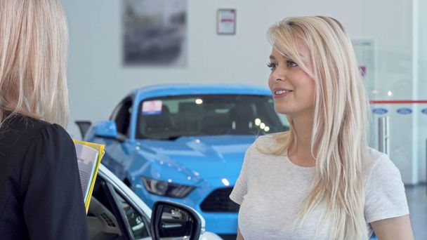 schöne Frau im Gespräch mit dem Verkäufer im Autohaus Salon - Foto, Bild