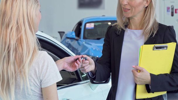 Cliente femminile che riceve le chiavi dell'auto, stringendo la mano con la commessa
 - Foto, immagini