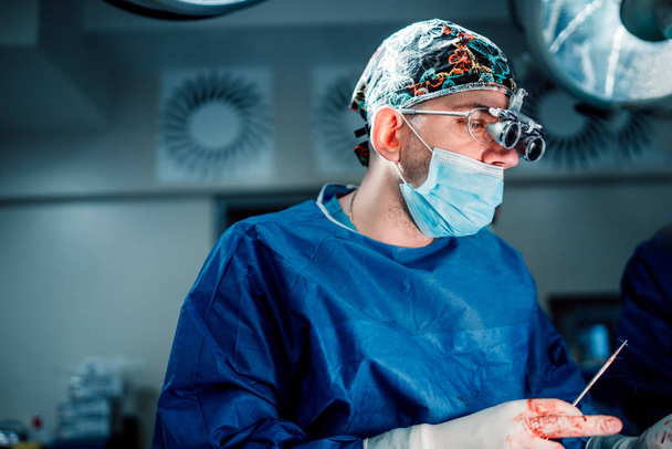 外科医医師がライトと医療機器手術に取り組んでいます。現代医学の詳細 - 写真・画像