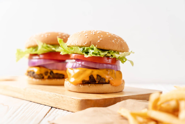 fresh tasty beef burger with cheese and french fries on wood background - Foto, afbeelding