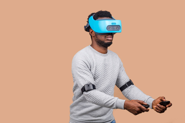 Black man wearing 3d vr glasses, playing videogame, holding gamepads in hands - Zdjęcie, obraz