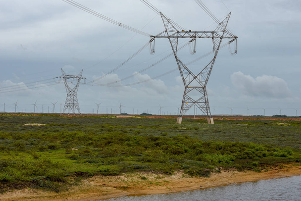 Tuulimyllyt ja sähkösäleiköt pellolla Atinsin lähellä Brasiliassa
 - Valokuva, kuva