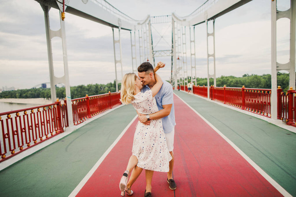 young stylish couple posing on pedestrian bridge - Foto, imagen