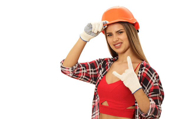 Happy beautiful female builder laughing showing sign of horns isolated on white copy space. Cool sexy woman carpenter showing rock and roll sign. Attractive female engineer. Emancipation concept - Valokuva, kuva