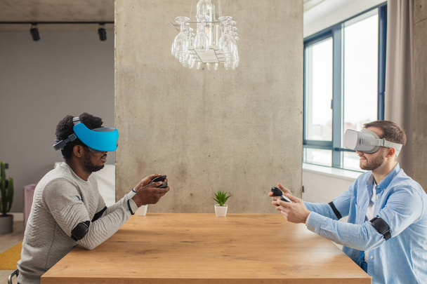 Twee uiteenlopende man in vrijetijdskleding zijn het ontwikkelen van een project met behulp van virtual reality bril. - Foto, afbeelding