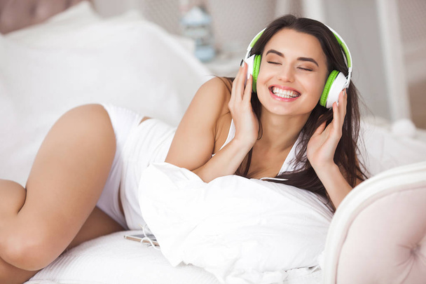 Jovem alegre ouvindo a música. Menina bonita usando fones de ouvido
 - Foto, Imagem