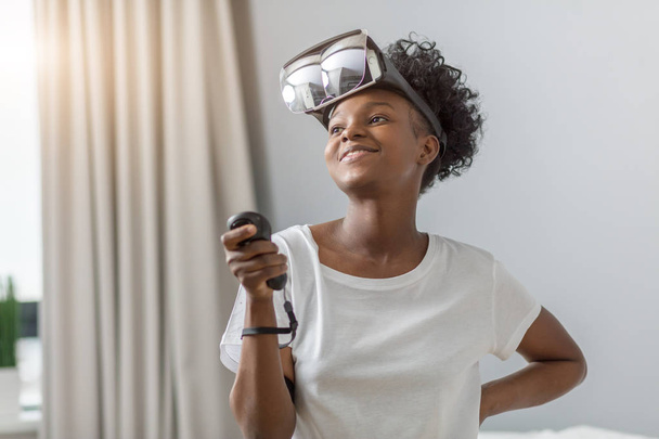 Beautiful african hipster girl dressed in white t-shirt making setting of head-mounted display with inserted inside smart phone, wearing on head - Fotoğraf, Görsel