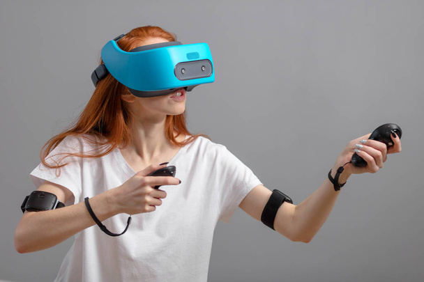 Redhead girl using VR glasses isolated over white. Virtual reality experience - 写真・画像