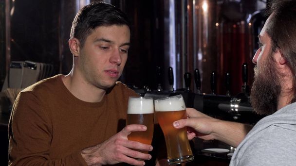 Giovane uomo godendo di bere deliziosa birra con il suo amico, occhiali tintinnanti
 - Foto, immagini