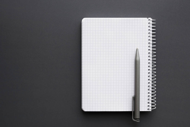 blank white notebook with pen over grey desktop - Foto, Bild