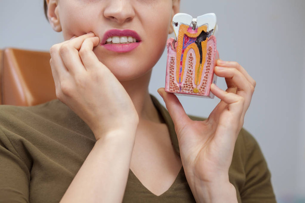 Обрезан крупным планом женщины, страдающей зубной болью, держащей зубную плесень с кариесом, копирующей пространство. Пациентка ждет стоматологического лечения в клинике. Стоматолог, концепция здоровья
 - Фото, изображение