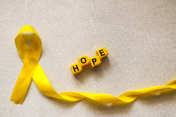 golden ribbon and words made up of children's plastic beeches. concept - a symbol of childhood cancer, pediatric oncology. - Fotoğraf, Görsel