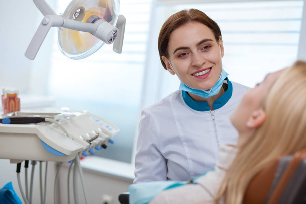 Wesoły kobieta dentysty uśmiechnięta radośnie, rozmowy z jej pacjent podczas badania stomatologicznego, kopiować miejsca. Przyjazny dentysta consulting jej klienta, działa Klinika stomatologiczna. Pojęcie opieki zdrowotnej - Zdjęcie, obraz