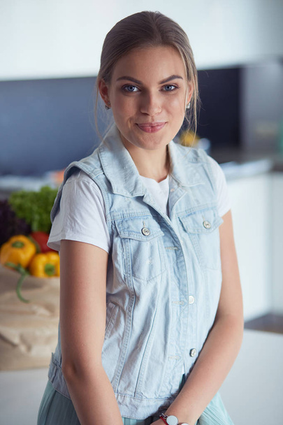 Kollarını mutfak arka planında kavuşturmuş genç bir kadının portresi. - Fotoğraf, Görsel