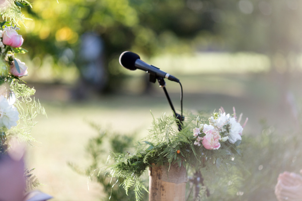 Квітковий букет і мікрофон на сцені на відкритому повітрі
 - Фото, зображення