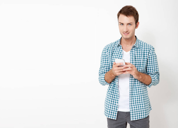 Attractive man with short dark hair chatting or typing text message using cell phone isolated over white background - Photo, Image