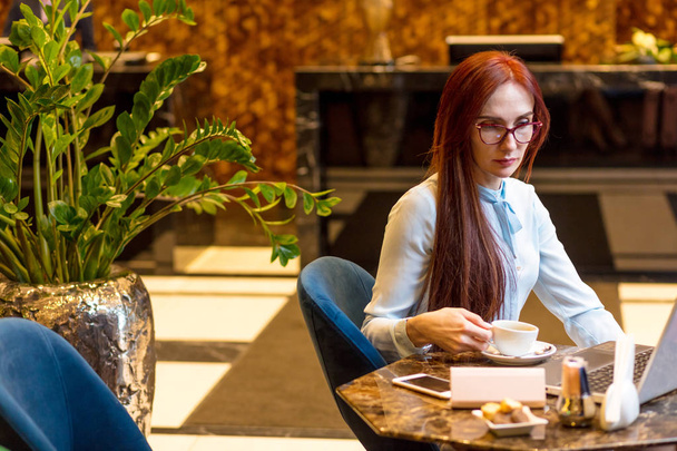 Business woman working at hotel lobby with laptop and drinking coffee - Foto, Imagen