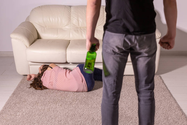 violenza domestica, alcolismo e abuso concetto - uomo ubriaco con bottiglia che abusa della moglie sdraiato sul pavimento
 - Foto, immagini