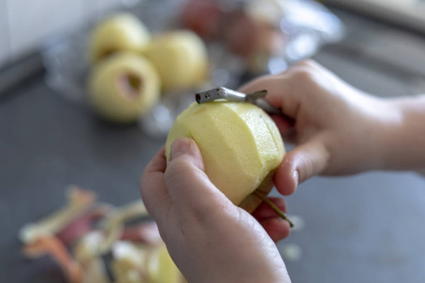 Mani che pelano una mela da cucina su fondo grigio
 - Foto, immagini