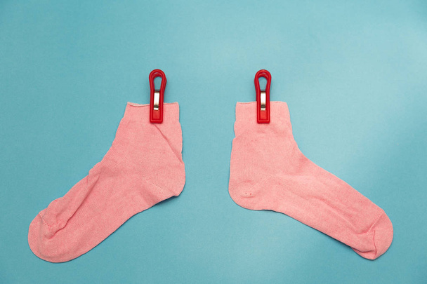 Pink socks on clothespins. Pink socks on blue background - Photo, Image