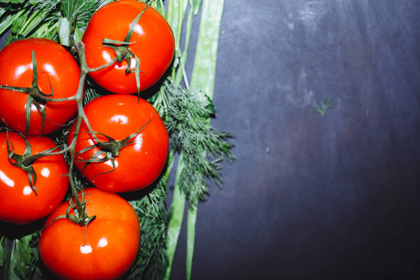 ripe tomatoes with herbs on black background. The whole vegetable, copy space. - 写真・画像