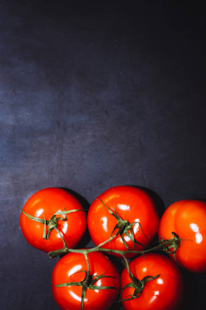 Red ripe tomatoes on a branch on a black background, copy space. - 写真・画像