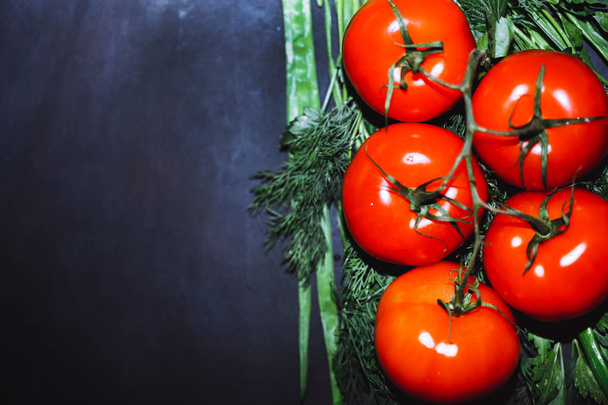 ripe tomatoes with herbs on black background. The whole vegetable. - 写真・画像