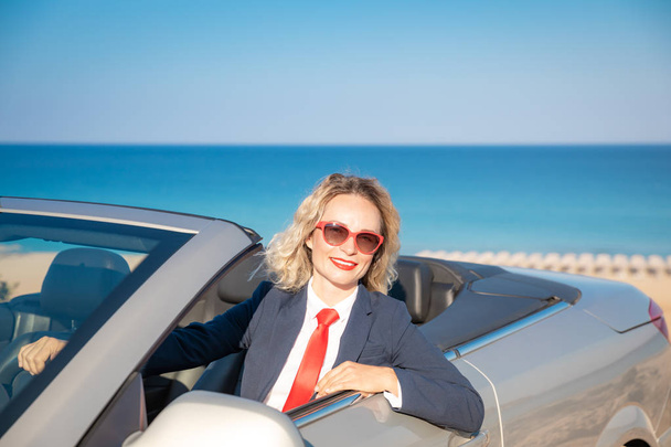 Successful young businesswoman on the beach. Woman sitting in the cabriolet classic car. Summer vacations and freedom travel concept - Foto, imagen