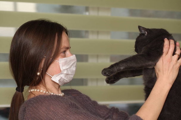 Mädchen mit medizinischer Maske auf dem Gesicht hält britische Katzenrasse.Toxoplasmose Schutz vor Katzeninfektion für Menschen. - Foto, Bild