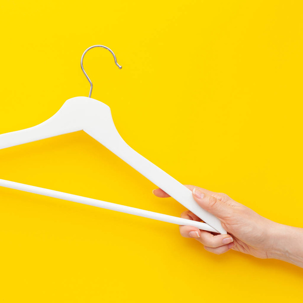 Creative top view flat lay white wooden hangers isolated bold yellow background with copy space minimalism style. Template fashion feminine blog social media sale store promo design shopping concept - Foto, Imagem