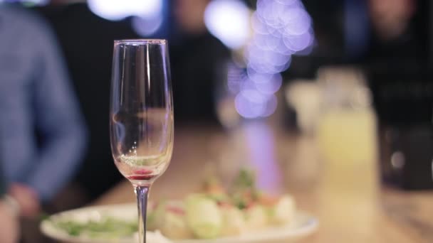 Vaso de champán vacío sobre la mesa sobre fondo borroso
 - Imágenes, Vídeo