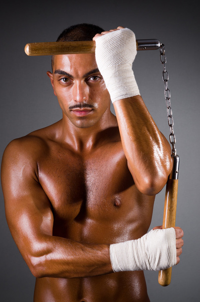muskulöser Mann mit Nunchucks auf weißem Grund - Foto, Bild