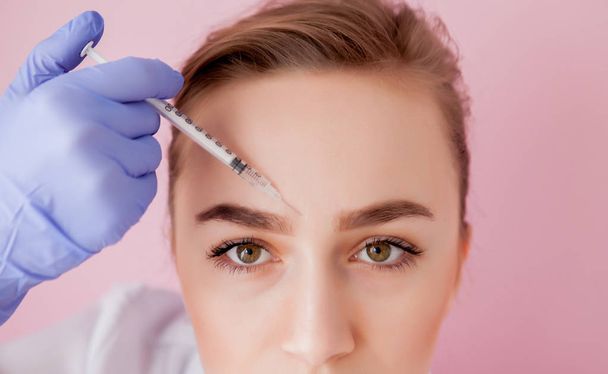 The doctor cosmetologist makes the Rejuvenating facial injections procedure for tightening and smoothing wrinkles on the face skin of a beautiful, young woman in a beauty salon.Cosmetology skin care. - Photo, Image