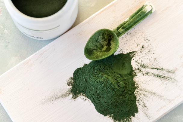 Grünes Spirulina-Algenpulver, gesunde Nahrungsergänzungsmittel auf Holzbrett - Foto, Bild