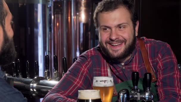 Przyjazny barman sakiewkach brzęczały szklanki z klientem, picie piwa - Materiał filmowy, wideo