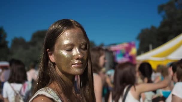 Dziewczyna, pokryta złotym brokatem cieszyć się w beach party - Materiał filmowy, wideo