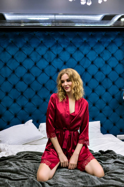 Cute  pretty woman in red robe on bed posing  - Valokuva, kuva