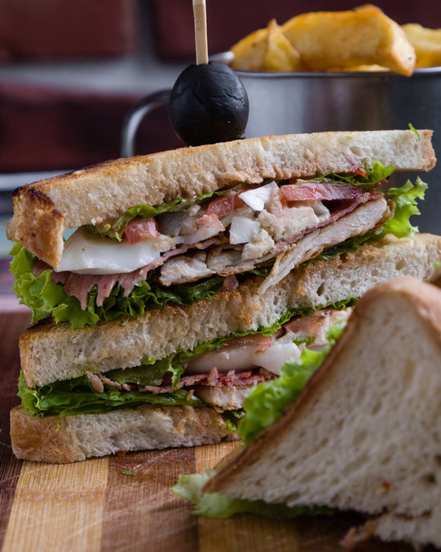 chutné kuřecí club sendvič s hranolky na dřevěný stůl - Fotografie, Obrázek