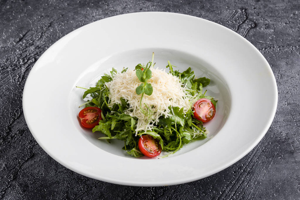 свежий вкусный салат из руколы в белой тарелке
 - Фото, изображение