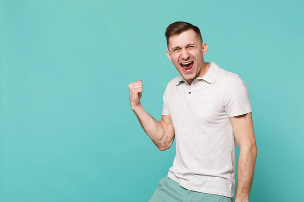 Портрет щасливого кричущого молодого чоловіка в повсякденному одязі, що стискає кулак, як переможець, ізольований на синьому бірюзовому фоні стіни в студії. Люди щирі емоції, концепція способу життя. Збільшити простір для копіювання
 - Фото, зображення
