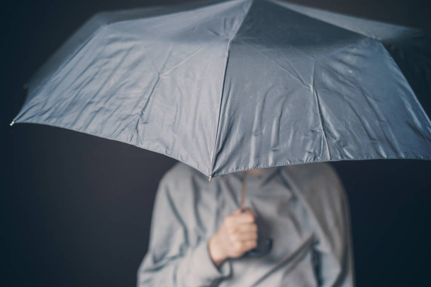 młody smutny człowiek trzymać parasol w złej pogody na ciemnym tle b d - Zdjęcie, obraz